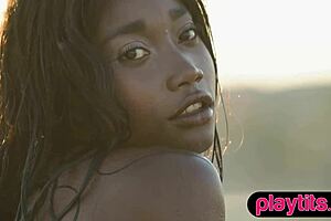 Petite ebony milf strips to expose her juicy round tits in a pool