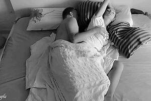 A quiet amateur couple shares an intimate spooning moment in bed late at night