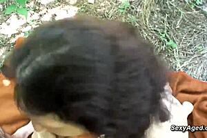 A hairy granny fucks wildly in the woods during midday heat